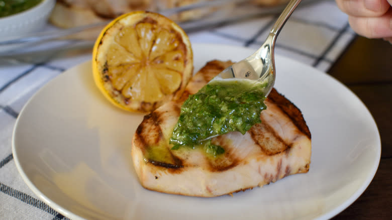 chef spooning herbs onto fish