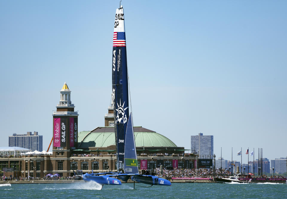 In this image provided by SailGP, the USA SailGP Team helmed by Jimmy Spithill sail past spectators at Navy Pier on Race Day 1 of United States Sail Grand Prix sailing race on Lake Michigan, Saturday, June 18, 2022, in Chicago. (Bob Martin/SailGP via AP)