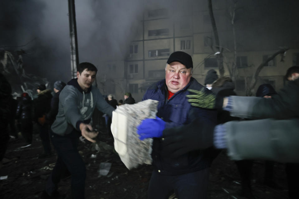 Local residents clear the rubble after a Russian rocket hit a multistory building leaving many people under debris in Dnipro, Ukraine, Saturday, Jan. 14, 2023. (AP Photo/Roman Chop)