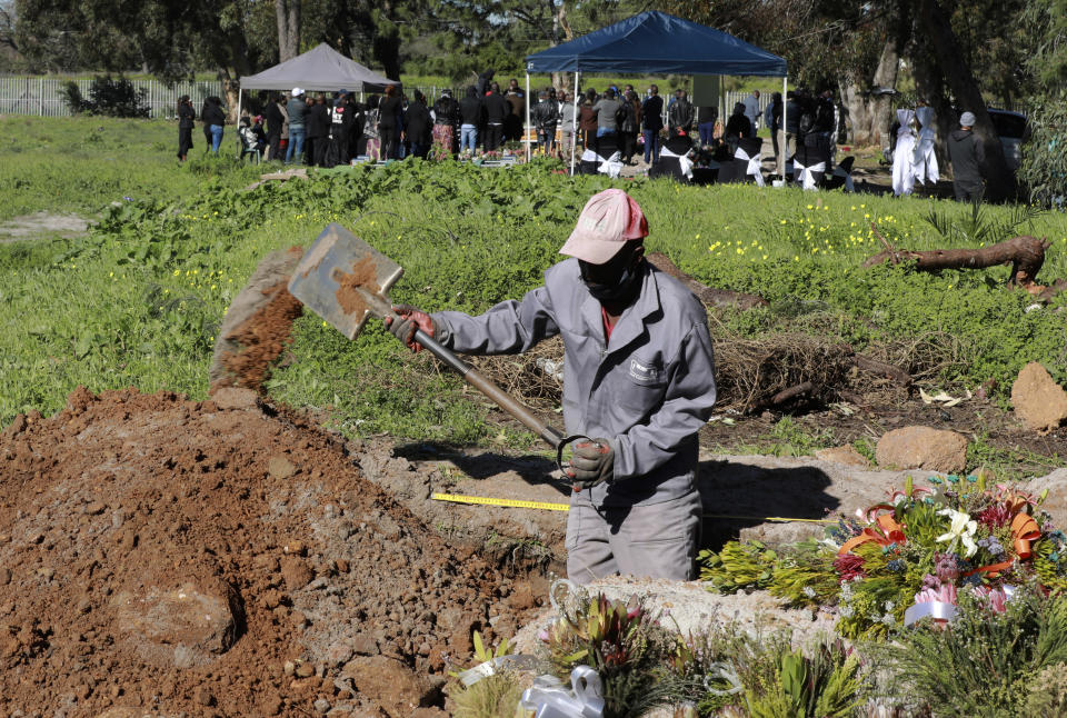 FILE - In this July 15, 2020, file photo, a grave digger prepares graves in the COVID-19 section of the Maitland Cemetary in Cape Town, South Africa as a burial takes place in the background. For months, the city of Cape Town was the biggest coronavirus hot spot in Africa. Now, finally, there are signs of relief. (AP Photo/Nardus Engelbrecht, File)