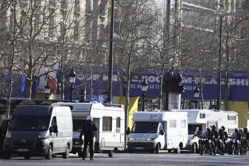 Police officers control camper vans on the Champs-Elysées avenue, Saturday, Feb.12, 2022 in Paris. Protesters angry over pandemic restrictions are driving toward Paris to blockade the French capital despite a police ban. The protesters organized online, galvanized in part by truckers who have blockaded Canada's capital. Paris region authorities deployed more than 7,000 police officers to tollbooths and other key sites to try to prevent a blockade. (AP Photo/Adrienne Surprenant)