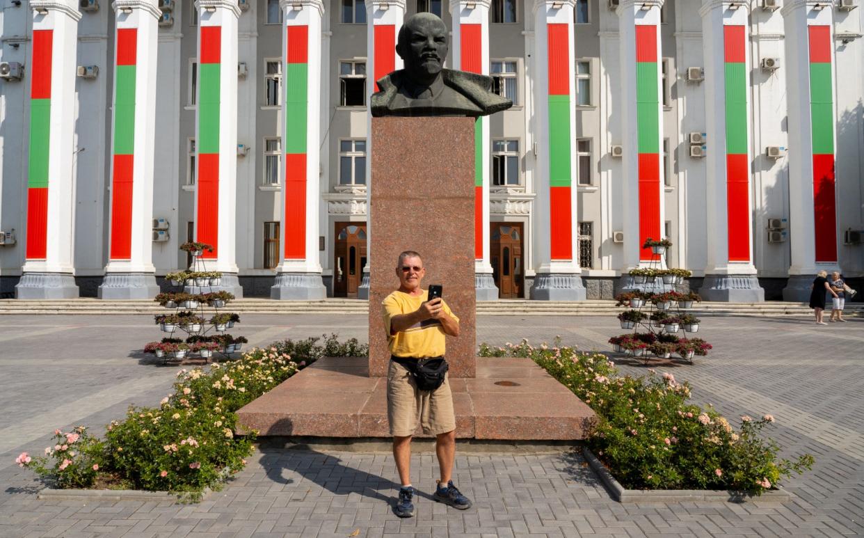 A Russian visitor takes a selfie with a bust of Lenin in front of the House of Soviets building