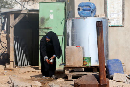 A Palestinian woman washes a pot from a tank outside her house on the outskirts of the West Bank village of Yatta, south of Hebron, August 17, 2016. REUTERS/Mussa Qawasma