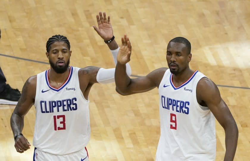 Los Angeles Clippers Paul George, left, and Serge Ibaka prepare to give high-five to teammates.