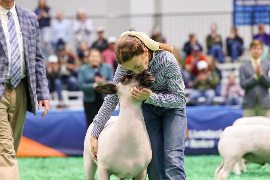 Stratley holds a sheep during a livestock show.