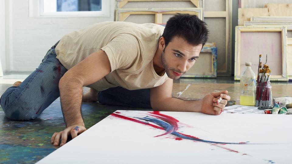 male fine artist painting in studio