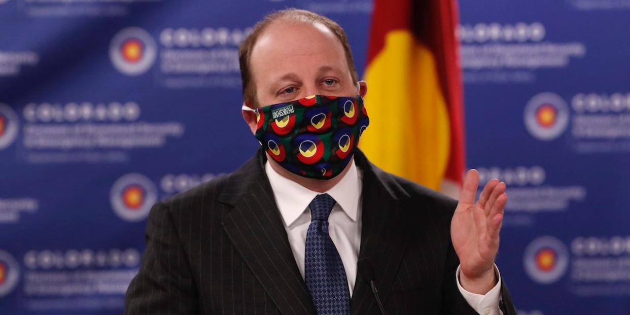 Colorado Gov. Jared Polis dons a mask to encourage state residents to wear them while in public as a statewide stay-at-home order remains in effect in an effort to reduce the spread of the new coronavirus.