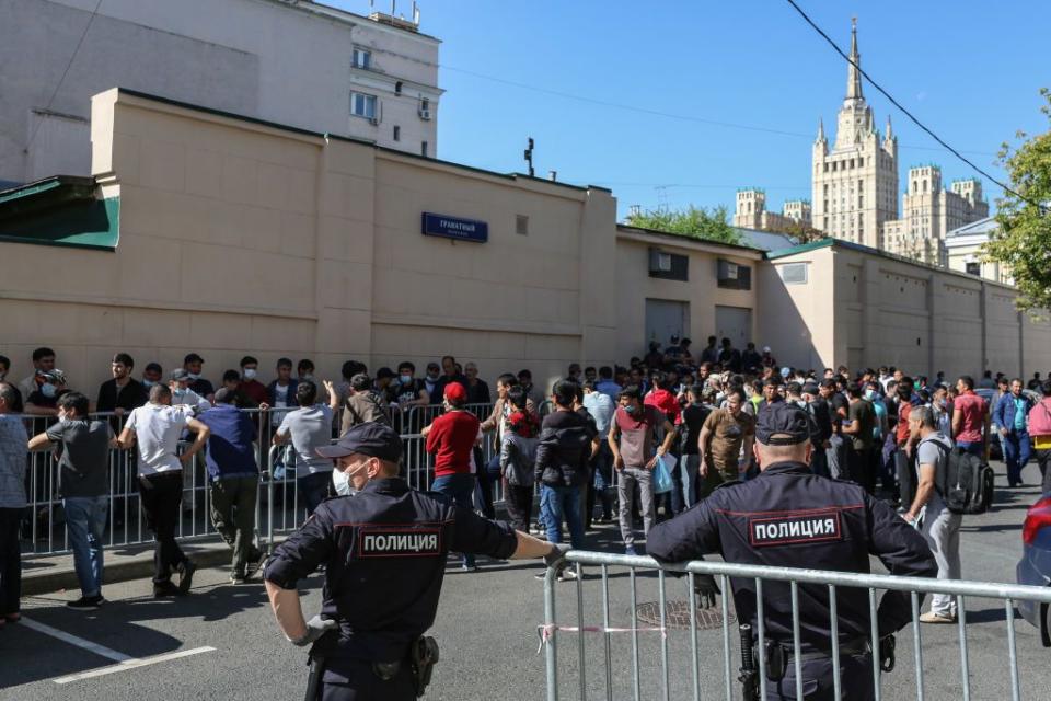 Police officers stand on patrol by a large crowd of people queuing outside the Tajik embassy in Moscow, Russia, on Aug. 10, 2020. (Andrey Rudakov/Bloomberg via Getty Images)