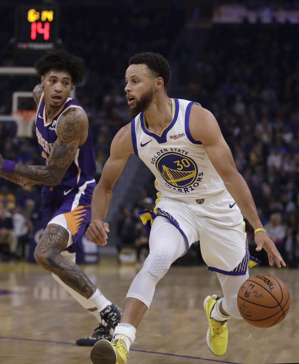 Phoenix Suns' Kelly Oubre Jr., left, guards Golden State Warriors' Stephen Curry during the first half of an NBA basketball game Wednesday, Oct. 30, 2019, in San Francisco. (AP Photo/Ben Margot)