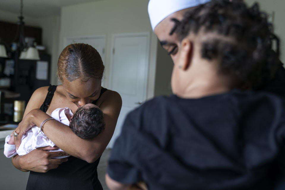 Aaliyah Wright, 25, of Washington, nuzzles their newborn daughter Kali, as her husband Kainan Wright, 24, of Washington, holds their son Khaza, 1, during a visit to the children's grandmother in Accokeek, Md., Tuesday, Aug. 9, 2022. A landmark social program is being pioneered in the nation’s capital. Coined “Baby Bonds,” the program is designed to narrow the wealth gap. The program would provide children of the city’s poorest families up to $25,000 when they reach adulthood. (AP Photo/Jacquelyn Martin)