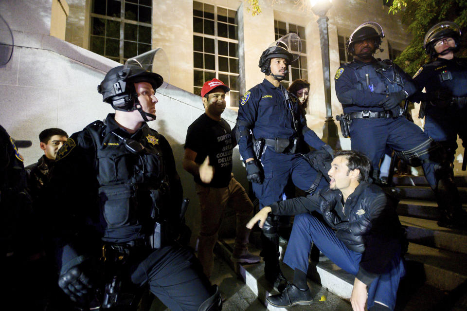 Police officers guard attendees leaving a speech by conservative commentator Ann Coulter on Wednesday, Nov. 20, 2019, in Berkeley, Calif. Hundreds of demonstrators gathered on campus as Coulter delivered a talk titled "Adios, America!" (AP Photo/Noah Berger)