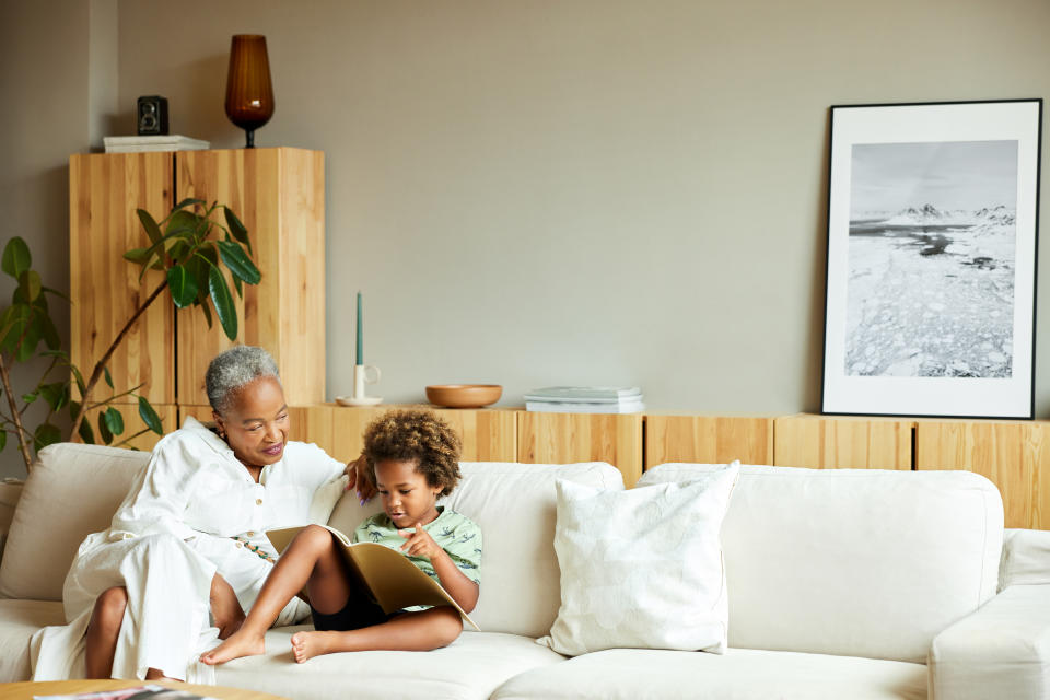 Adult and child reading a book together on a sofa in a cozy room setting