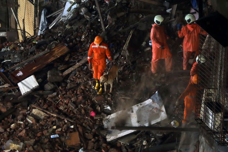 National Disaster Response Force (NDRF) personnel look for survivors trapped in the debris with a sniffer dog after part of a residential building collapsed after heavy rains in Mumbai