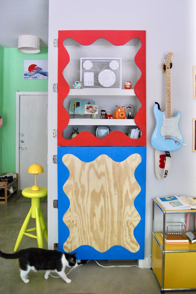 Red scalloped frame over shelves in eclectic apartment.