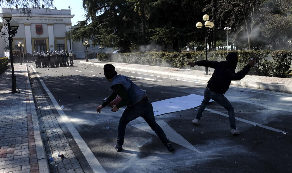 Protesters throw stones at policemen during an anti-government rally in Tirana, Albania, Saturday, March 16, 2019. Albanian opposition supporters clashed with police while trying to storm the parliament building Saturday in a protest against the government which they accuse of being corrupt and linked to organized crime. (AP Photo/Hektor Pustina)