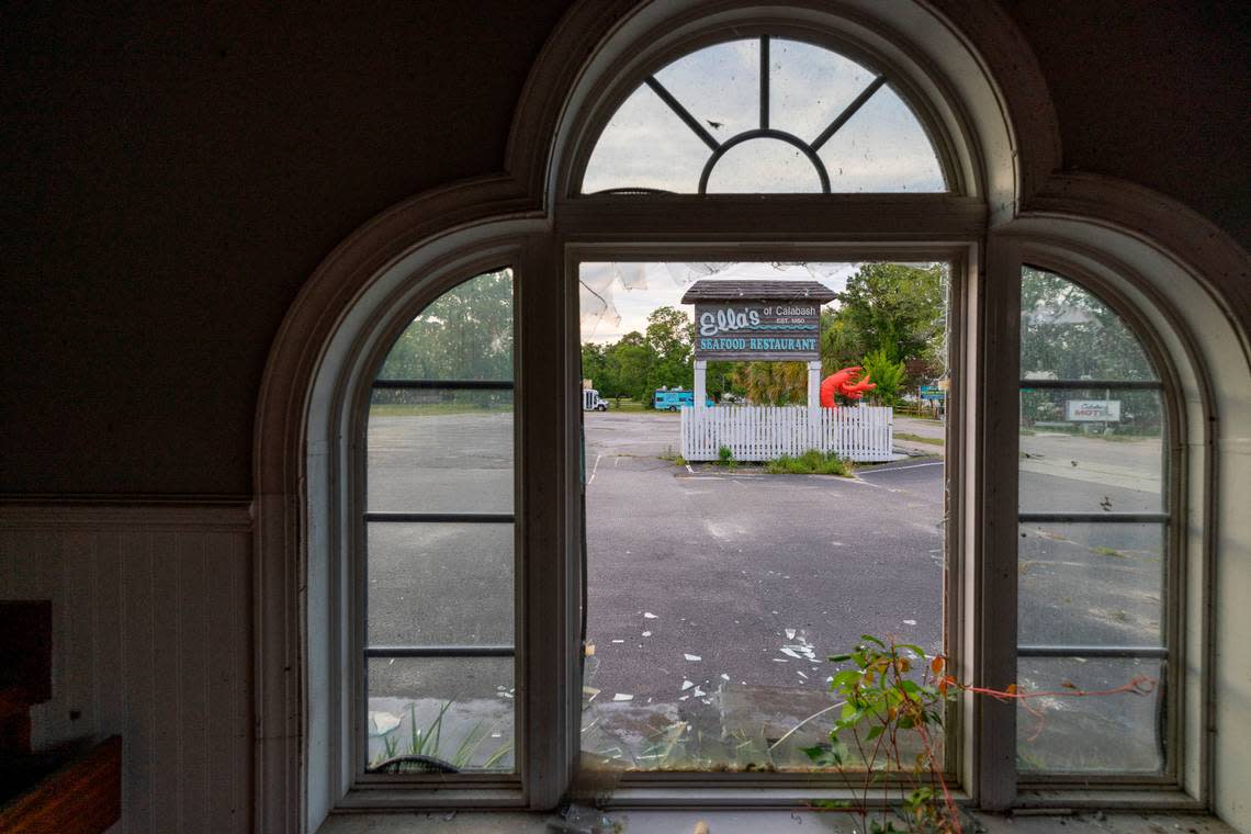 The remnants of the famed Ella’s Restaurant, destroyed by a fire in 2023 frame the sign for the restaurant on Wednesday, July 12, 2024 in Calabash, N.C . In recent weeks the debris has been cleared as the family works to rebuild.