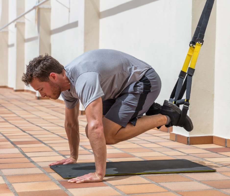 How to do it:<ul><li>Start in pushup position with hands beneath shoulders and each foot inside a suspension trainer strap so the straps hang vertically.</li><li>While keeping your shoulders stable, pull your knees toward your chest.</li><li>Move slow and controlled.</li></ul>