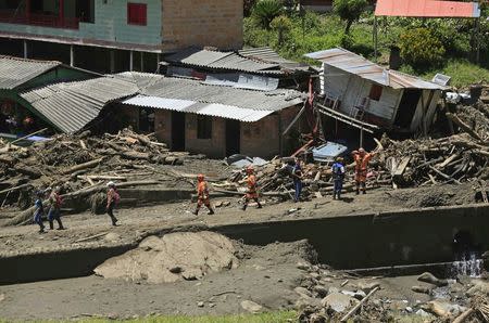 Rescue workers walk past houses that were destroyed after a landslide sent mud and water crashing onto homes close to the municipality of Salgar in Antioquia department, Colombia May 19, 2015. REUTERS/Jose Miguel Gomez