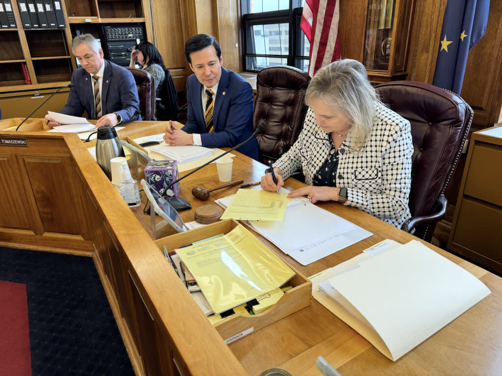 Rep. DeLena Johnson, R-Palmer and co-chair of the House Finance Committee, signs the committee's version of the state operating budget on Friday, April 5, 2024. Looking on is Rep. Neal Foster, D-Nome, and at background is Rep. Frank Tomaszewski, R-Fairbanks. (Photo by James Brooks/Alaska Beacon)