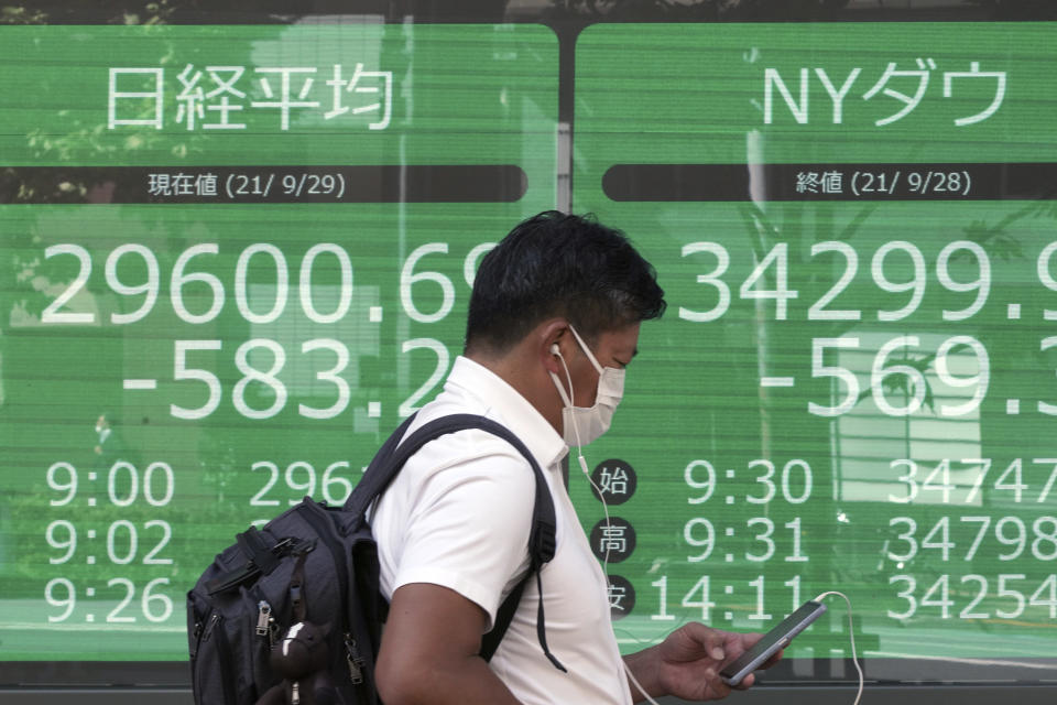 A man wearing a protective mask walks in front of an electronic stock board showing Japan's Nikkei 225 and New York Dow indexes at a securities firm Wednesday, Sept. 29, 2021, in Tokyo. Asian shares fell sharply on Wednesday after a broad slide on Wall Street as investors reacted to a surge in U.S. government bond yields. (AP Photo/Eugene Hoshiko)