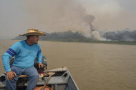 Daniel Moura, an eco-tourism guide, rides his boat on the Cuiaba river as fires burn in the Encontro das Aguas Park near Pocone, Mato Grosso state, Brazil, Saturday, Sept. 12, 2020. The Pantanal, the world’s largest tropical wetlands and a biodiversity hot spot, this year is exceptionally dry and burning at a record rate. (AP Photo/Andre Penner)