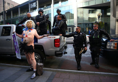 A man in a Trump outfit poses in front of a group of Seattle Police officers at Westlake Park on May Day in Seattle, Washington, U.S. May 1, 2018. REUTERS/Lindsey Wasson