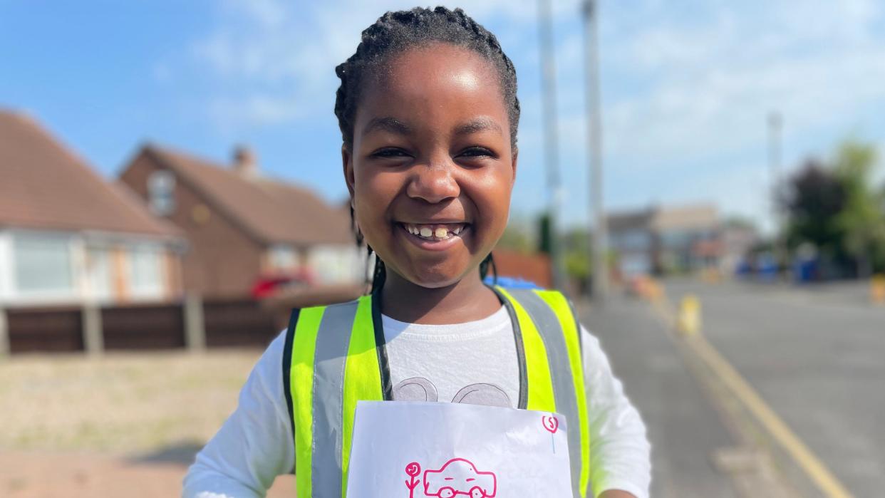 Child in a high viz jacket holding a leaflet