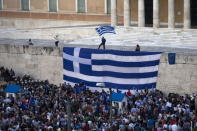 A protester waves a Greek flag at the entrance of the parliament building during a rally calling on the government to clinch a deal with its international creditors and secure Greece's future in the Eurozone, in Athens, Greece, June 22, 2015. REUTERS/Marko Djurica