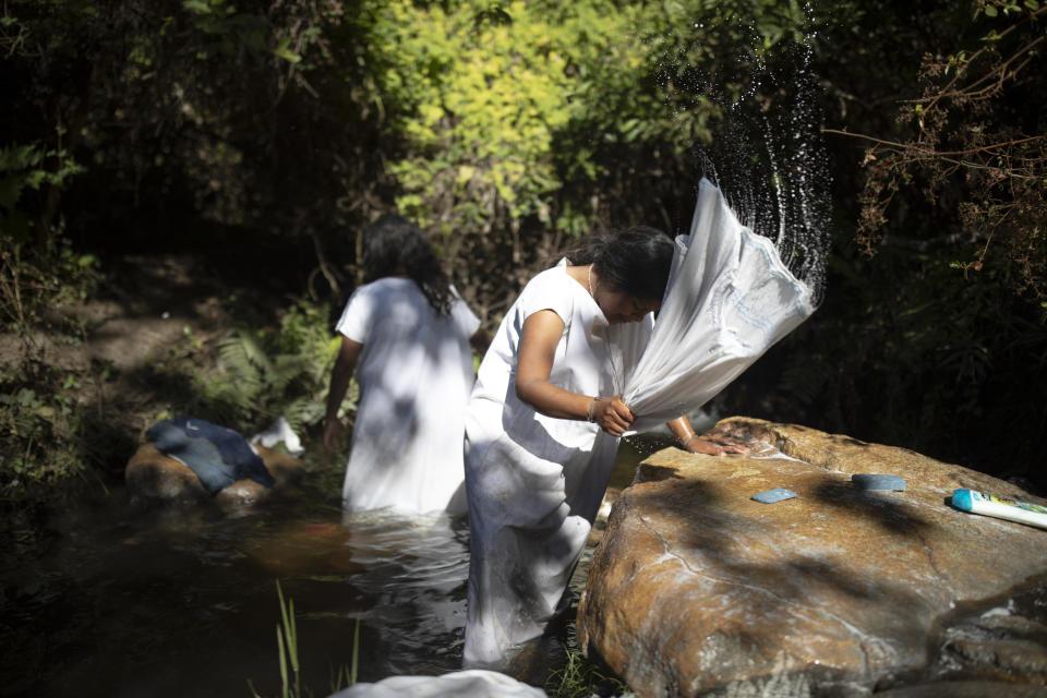 Mujeres indígenas arhuacos lavan ropa en un arroyo en Nabusimake en la Sierra Nevada de Santa Marta, Colombia, el martes 17 de enero de 2023. (AP Foto/Iván Valencia)