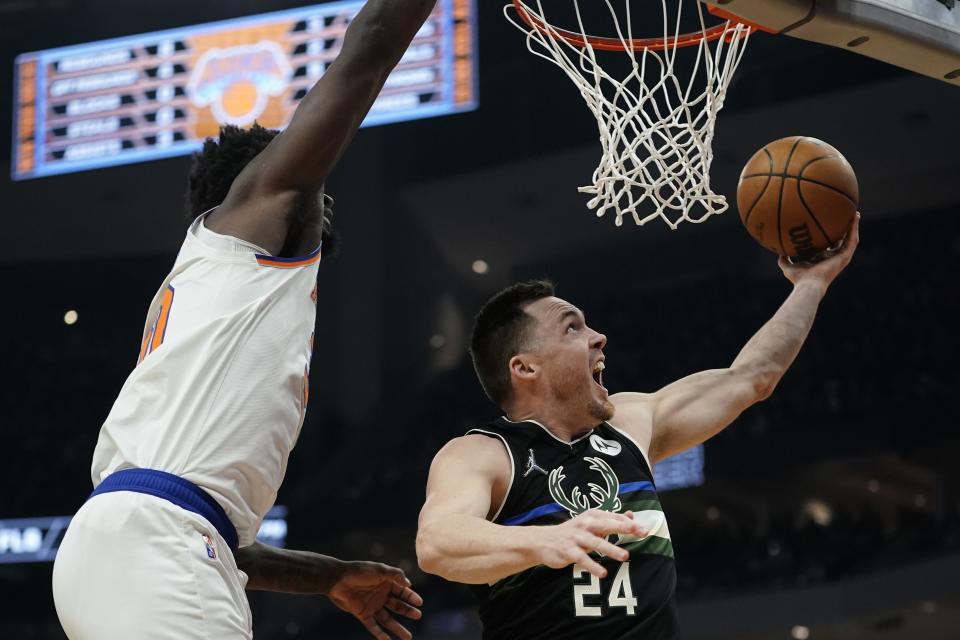 Milwaukee Bucks' Pat Connaughton shoots past New York Knicks' Julius Randle during the first half of an NBA basketball game Friday, Jan. 28, 2022, in Milwaukee. (AP Photo/Morry Gash)