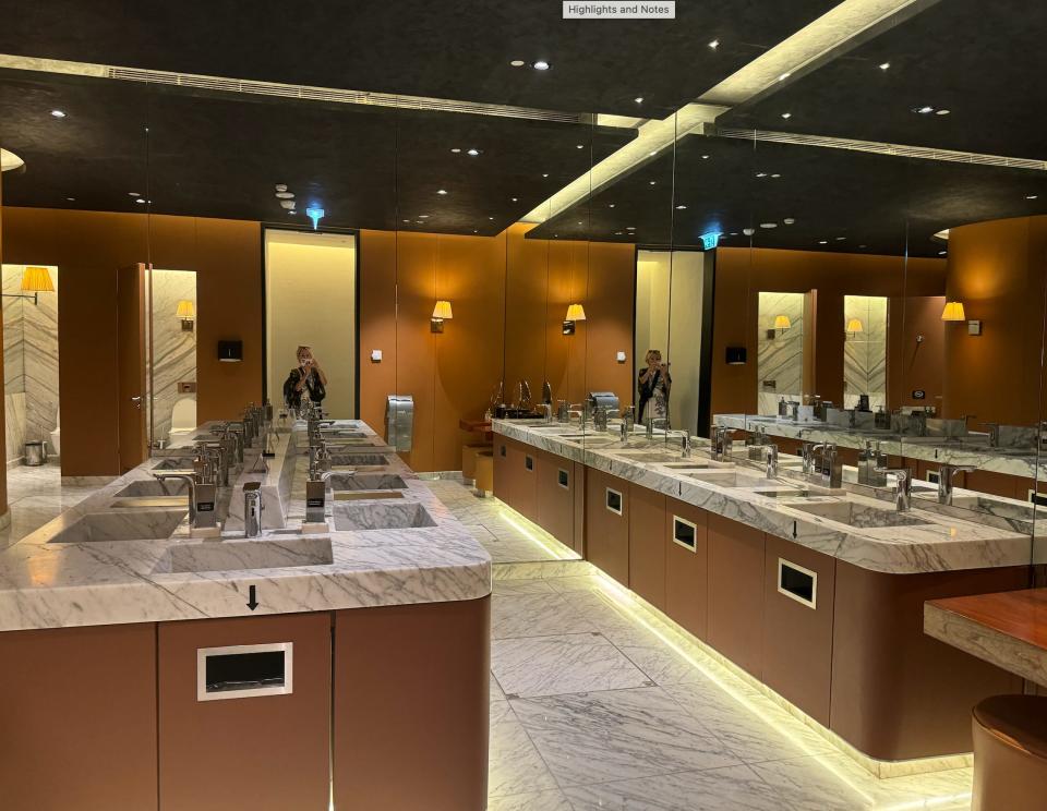 A large bathroom with lots of marble sinks and mirrors.