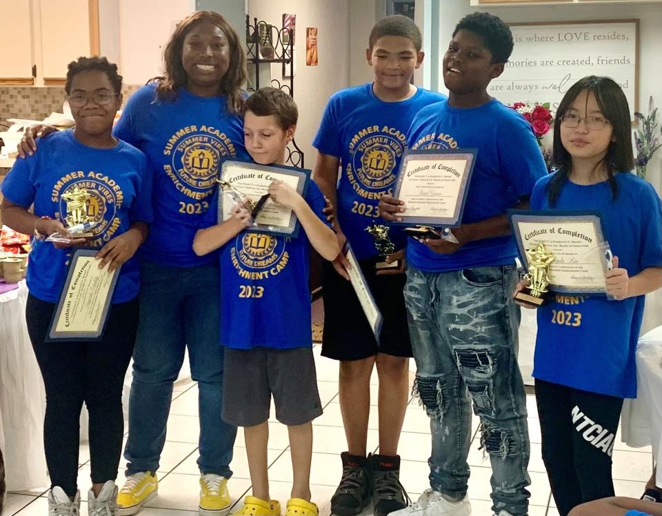 Tayvia Eaddy, teacher Jhane’ Carter, Liam Milligan, Donte Benyard, Israel Green and Angela Lin share a moment of achievement with certificates awarded at the Summer Academic Enrichment Camp, sponsored and administered by the Harry T. and Harriette V. Moore Cultural Complex board of directors in North Brevard.