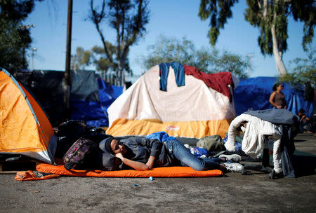 A migrant, part of a caravan of thousands from Central America trying to reach the United States, shelters as he rests on a street in Tijuana, Mexico, December 7, 2018. REUTERS/Mohammed Salem