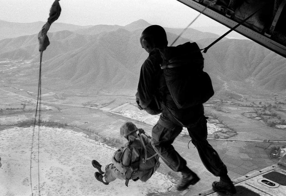 American paratrooper jumps with other buddies as U.S. forces unleashed the greatest ground-air assault of the Vietnam war, Feb. 23, 1967. The drive, ranging 50 to 75 miles northwest of Saigon, began Feb. 22 with a drop of about 700 paratroopers into blocking positions behind Viet Cong lines from Cambodia. The paratroopers took off from Bien Hoa airbase.   (AP Photo)