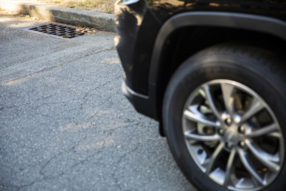 A car tire drives past a storm drain.