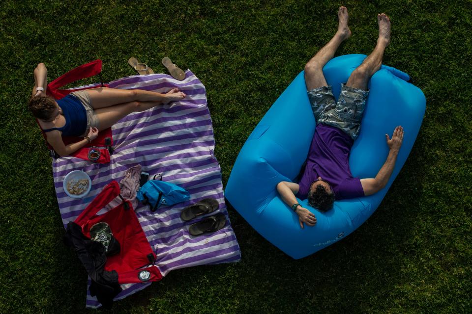 Spectators lounge in the grass beneath the Big Four Bridge during  the second Waterfront Wednesday of the year. May 29, 2019