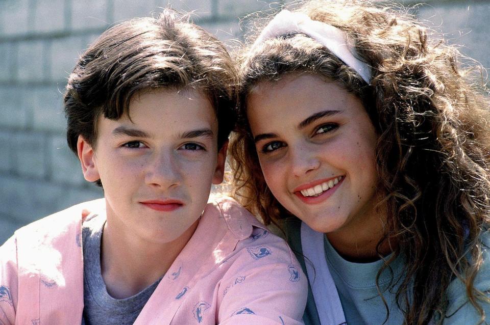 keri russell smiles at the camera, shwe wears a blue shirt and white headband