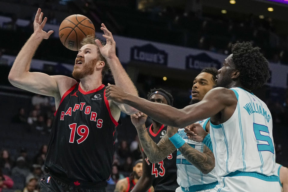 Toronto Raptors center Jakob Poeltl vies for the ball with Charlotte Hornets center Mark Williams and forward P.J. Washington during the first half of an NBA basketball game Friday, Dec. 8, 2023, in Charlotte, N.C. (AP Photo/Chris Carlson)