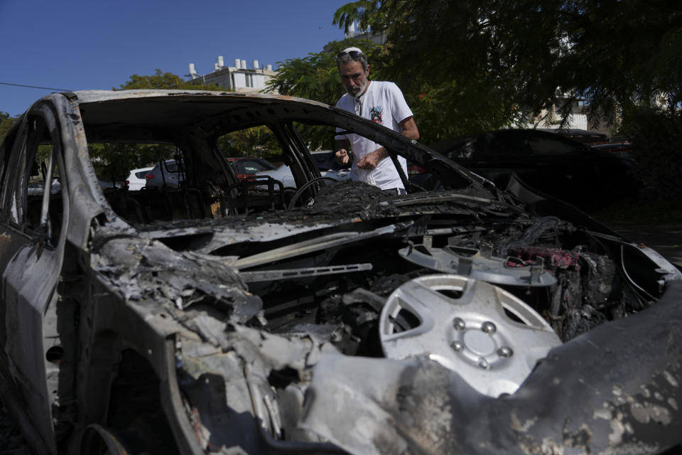 A man looks at the car destroyed by a rocket fired from the Gaza Strip in Ashkelon, Israel, Saturday, Oct. 21, 2023. (AP Photo/Tsafrir Abayov)