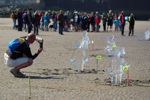 Members of the public look at some of 26 ice sculptures of children installed on New Brighton Beach, Wallasey in Merseyside