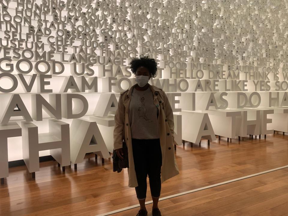 Cornelia Poku standing in front of wall of words at the planet Word Museum