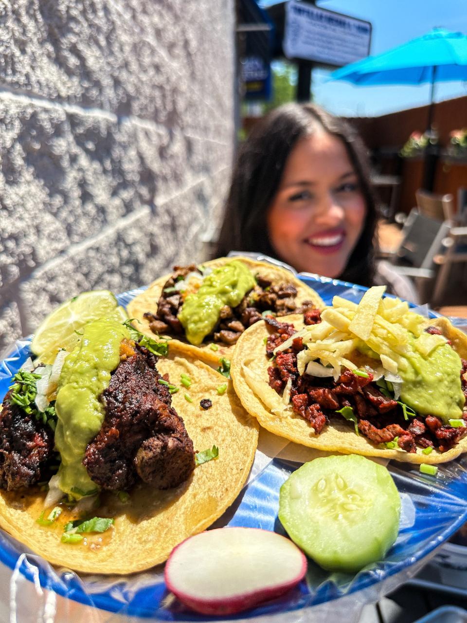 A photo of Erica Noblecilla sat outside holding a taco tray