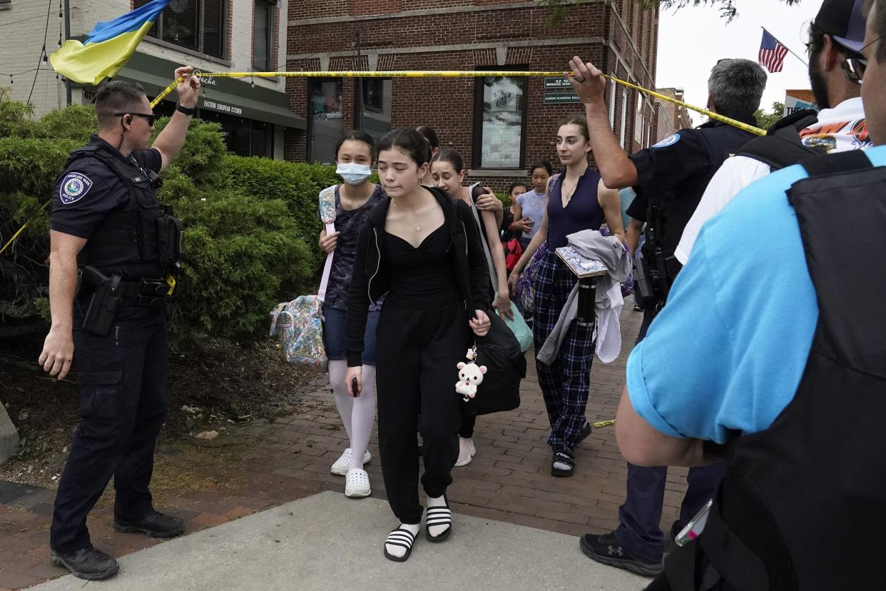 Students are escorted by police officers as they cross under police tape after a mass shooting at the Highland Park Fourth of July parade in downtown Highland Park, Ill., a Chicago suburb, on Monday, July 4, 2022.