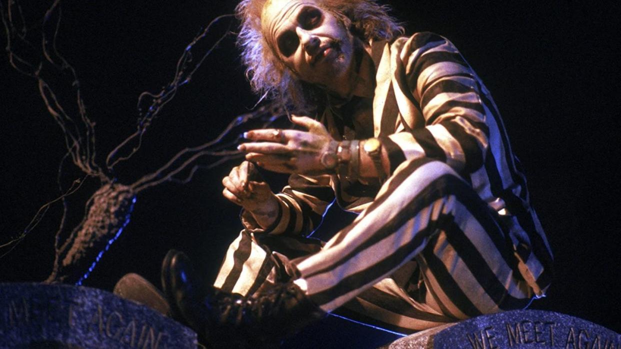 beetlejuice sits in his striped suit in a scene from beetlejuice a good housekeeping pick for best halloween movies