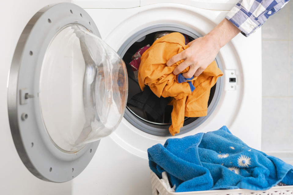 persons hand put dirty clothes in the washing machine