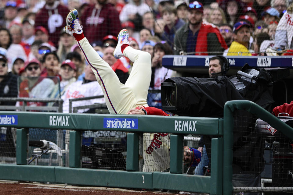 Philadelphia Phillies' Bryce Harper falls into the dugout as he gives chase for a foul ball during the first inning of a baseball game against the Atlanta Braves, Saturday, March 30, 2024, in Philadelphia. (AP Photo/Derik Hamilton)
