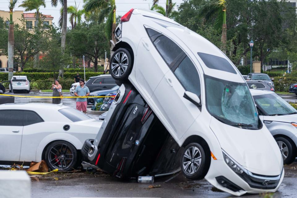 Passers-by photograph a pileup of vehicles at The Point apartment complex in Palm Beach Gardens on Sunday in the aftermath of a Saturday evening tornado.