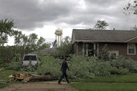 A man walks past a damaged house and tree after a tornado passed through the area on Monday, June 21, 2021, in Woodridge, Ill. (AP Photo/Shafkat Anowar)