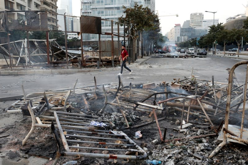 A man walks past debris at a site of protest that happened yesterday over deteriorating economic situation in Beirut