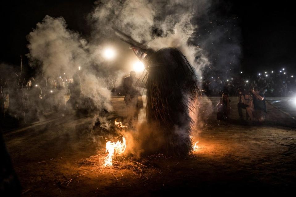 A performer wearing the traditional kumbo mask, a mythological figure of the Jola tribe dressed with palm leaves, whirls in fire during the kankurang Festival in Janjanbureh on January 27, 2024. Listed as a UNESCO World Heritage Site since 2005, Kankurang, a combination of the Mandingo words 